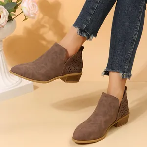 Detailweergave van bruine suède Chelsea boots met bloemenuitsnijdingen en lage hak
