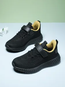 Close-up of breathable black knit children's running sneakers with yellow lining detail.