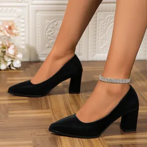 Side view of elegant black pointed-toe block heel pumps worn by a model in a room