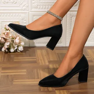 Close-up view of elegant black pointed-toe block heel pumps worn by a model on wooden floor