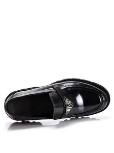 Detailed view of shiny black patent leather chunky loafers with silver triangle logo