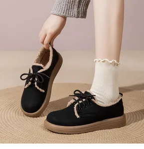 Primo piano di scarpe nere foderate in pile con suola marrone spessa e lana calda