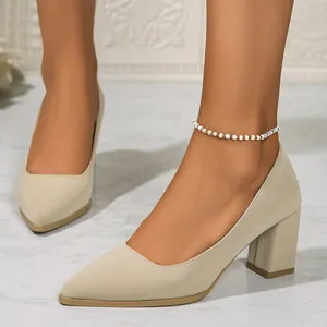 Elegant beige pointed-toe block heel pumps shown on feet with a chic beaded anklet detail.