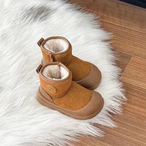 Detailed view of camel children's snow boots with soft plush lining on white fur rug