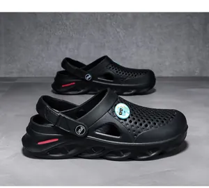 Detalle lateral de zuecos negros para hombre con diseño transpirable y dije de dinosaurio