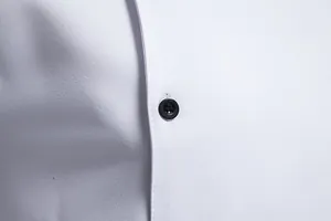 Primer plano del tejido de alta calidad y botón negro de una camisa blanca de hombre