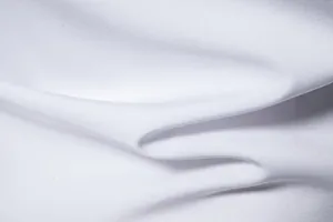 Detalle de primer plano que muestra la textura de la tela blanca de una camisa para hombres.