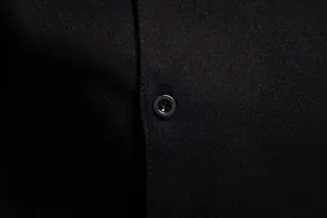 Detalle macro de un botón negro y la textura de la tela en una camisa de hombre.