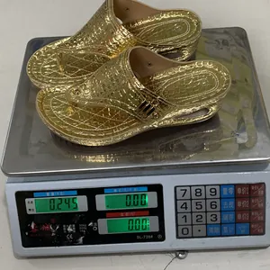 Detail view of gold crocodile embossed platform flip-flops being weighed on a digital scale