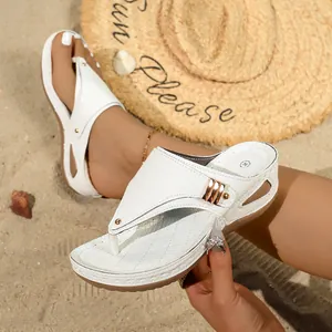 Close-up of white snake-textured platform thong sandals with gold buckle detail.