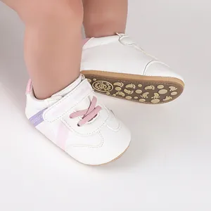 Nahaufnahme weißer Baby-Lauflernschuhe mit rosa Akzenten und rutschfester Gummisohle.