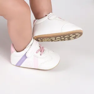 Weiße Lauflernschuhe für Babys aus Kunstleder mit rosa Schnürsenkeln und Antirutschsohle.