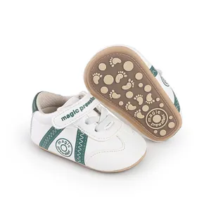 Weiße und grüne Baby-Lauflernschuhe mit rutschfester brauner Sohle und Fußmustern