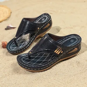 Stylish black snake texture wedge flip-flop sandals displayed on sunny beach sand