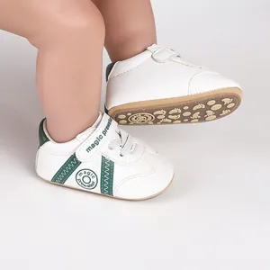 Weiße und grüne Baby-Lauflernschuhe mit rutschfester Sohle und Klettverschluss.
