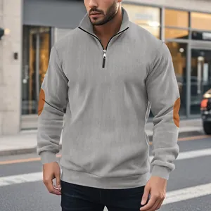 Detailansicht des grauen Cord-Sweatshirts mit halbem Reißverschluss und Ellbogen-Patches.