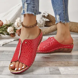 Vista detallada de las sandalias con cuña rojas con textura de cocodrilo y punta abierta
