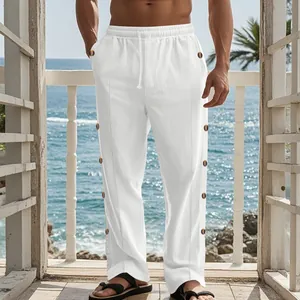 Détail de ce pantalon en lin blanc avec boutons latéraux et taille à cordon de serrage.