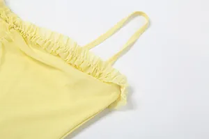 Close-up detail of the yellow mesh camisole dress showing delicate ruffled trim.