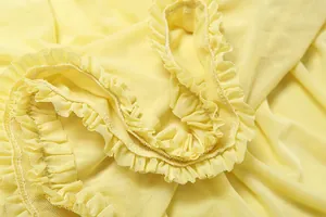 Macro view of the delicate yellow ruffle trim and mesh fabric texture of a dress