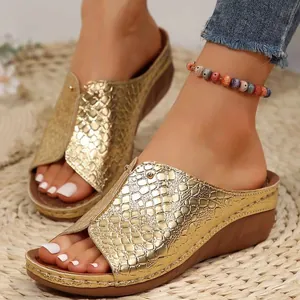Detalle de sandalias de cuña doradas para mujer con diseño de piel de serpiente