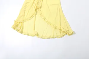 Close-up detail of the ruffled hem and sheer mesh fabric on this yellow maxi dress