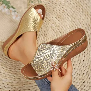 Vista detallada de sandalias de cuña doradas para mujer con textura de cocodrilo y flores