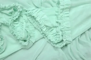 Close-up of light green mesh fabric with ruffled edge detail on a sexy slim-fit long dress.