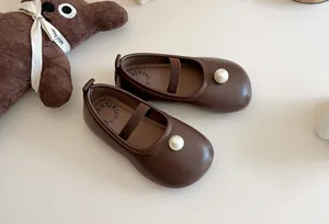 Detailed view of elegant brown Mary Jane shoes for girls featuring a signature pearl accent.