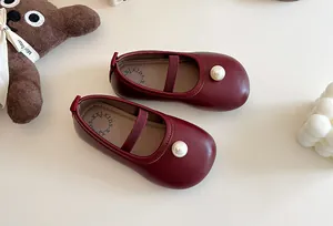 Close-up of red girl's Mary Jane leather shoes with pearl detail and elastic strap