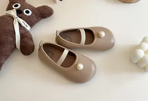 Detailed view of beige girls' Mary Jane shoes featuring a large pearl embellishment.
