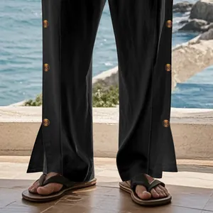 Gros plan sur un pantalon en lin noir pour homme avec boutons latéraux et fentes.