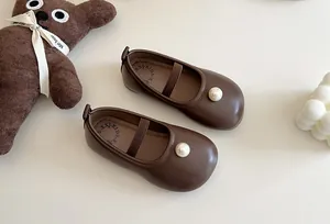 Detailed close-up of brown girls' Mary Jane shoes featuring elegant pearl embellishments