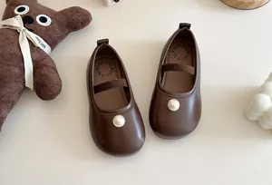 Close-up of brown Mary Jane shoes for girls with pearl accent and bear plushie
