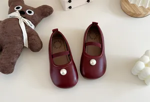 Close-up of burgundy girls' Mary Jane shoes featuring a white pearl accent and elastic strap