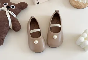 Close-up of khaki toddler Mary Jane shoes featuring a large pearl and elastic strap