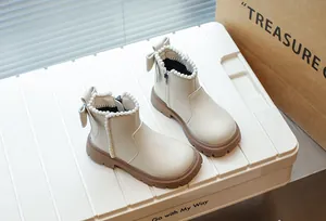 Détail de bottines crème pour filles avec bordure en perles et décoration de nœud