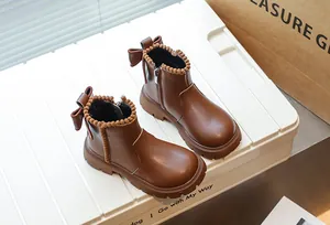 Gros plan de bottines marron pour enfants avec un nœud mignon et une bordure en pompons