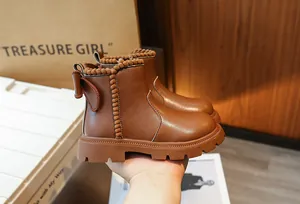 Gros plan détaillé des bottines Chelsea marron pour filles avec nœud et pompons décoratifs