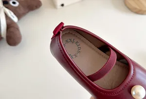 Detail shot of girls' burgundy Mary Jane leather shoes with an elegant pearl accent