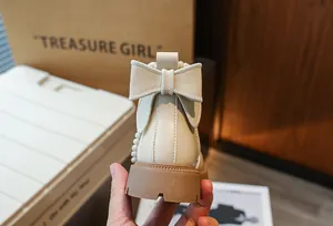 Vue détaillée d'une botte Martin beige pour fille avec un nœud décoratif au talon.