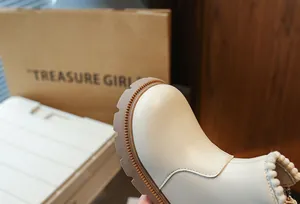 Détail en gros plan de la texture du cuir crème des bottes Martin pour filles