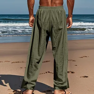 Vue arrière d'un pantalon décontracté en lin vert olive pour homme sur une plage ensoleillée.