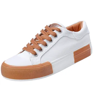 Fashionable white men's canvas sneakers featuring brown laces and durable rubber sole accents