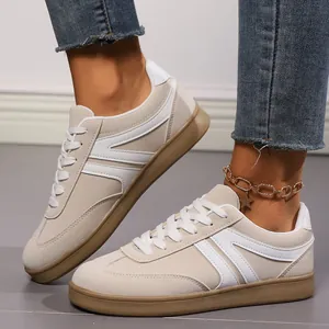 Detailed view of women's vintage beige flat sneakers featuring white stripes and laces