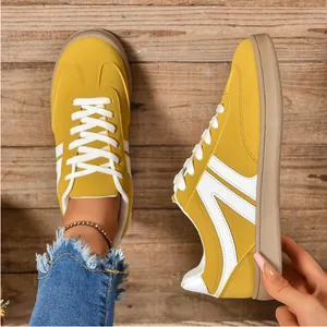 High-quality detail view of yellow retro women's casual sneakers on a rustic wooden floor