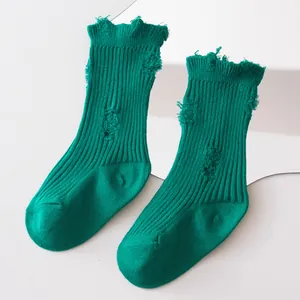 Close-up of green ribbed distressed socks with stylish ripped hole design details