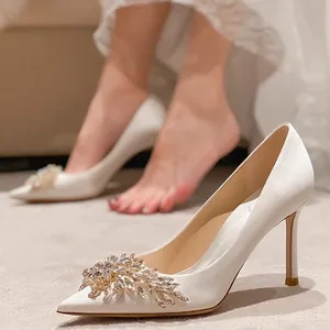 Détail d'une fleur en cristal sur d'élégantes chaussures de mariage en satin blanc à talons