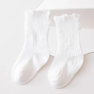 Detailed view of white distressed mid-tube children socks with ruffled cuffs and ribbed knit
