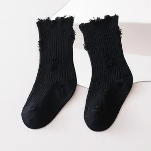 Detailed texture of black distressed mid-calf socks for kids with trendy ripped design